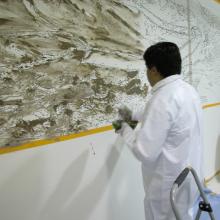 A man paints with mud on a wall