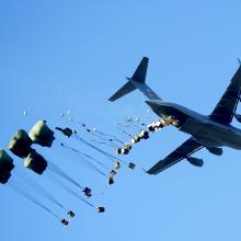 A plane airdropping a number of packages. 