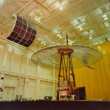 Applications Technology Satellite-6 (ATS-6), an umbrella shaped satellite is in the middle of a large interior space.