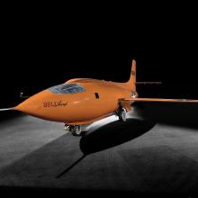 Bell X-1 aircraft photographed from a side angle against a dark backdrop