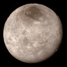 Disk view of Charon, one of Pluto's moons, which has a gray and brown color.