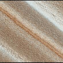 An image of mars surface showing stripes of different hues of reds, oranges, browns, and whites.