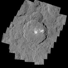 A view of the rough surface of Ceres with a cluster of white spots at the center of a crater.