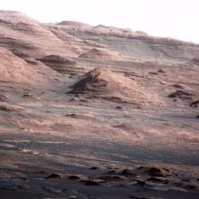 Jagged rocks on Mars jut out of the ground, each demonstrating their layered history through different bands of colors.