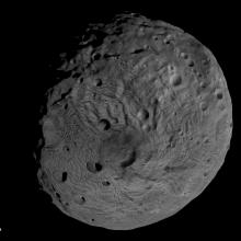 A globe shaped asteroid with a cratered surface. 