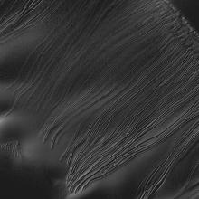 A dark grey image featuring lines, known as linear gullies, on the surface on Mars.