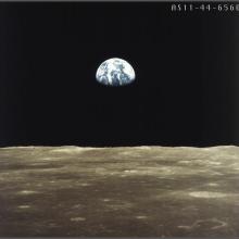 An image taken from the surface of the Moon looking toward Earth. The bottom one-fourth of the Earth is shrouded in darkness.