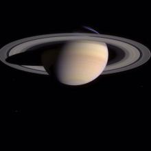 Saturn as seen from the bottom half up. A spot can be seen on the bottom left of the planet.