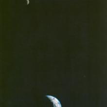 A photo of the Earth and Moon in the same frame. The Moon is in the upper left and the Earth is at the bottom of the frame in the middle.