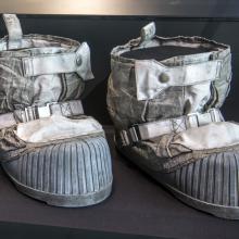 A pair of space boots are on displayed in an enclosed case