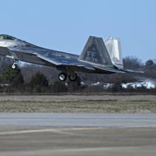 F-22 Raptor fighter jet taking off from a runway.