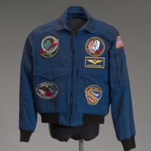 A blue NASA flight jacket covered in various mission patches.