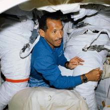 A man floats through two space suits aboard the Space Shuttle.