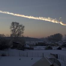 A photograph of a streak of vapor in the sky over a snowy village. 