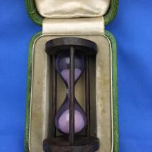 Small hourglass in a box lined with purple fabric