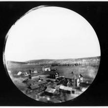 An image of a village from up high. The image itself looks as if it was taken through a peep hole. 