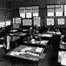 A photo of a group of people sitting at desks inspecting various images.