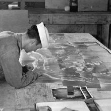 A photo of a person inspecting a large array of photos that have pieced together to create one large image.