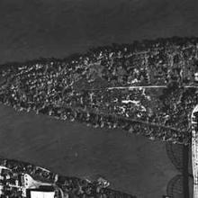 An aerial photo of a triangular shaped island that has a bridge connecting it to the mainland.