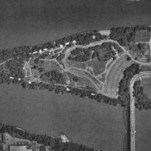 An aerial photo of a triangular shaped island that has a bridge connecting it to the mainland.