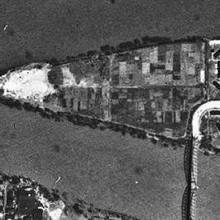 An aerial photo of a triangular shaped island that has a bridge connecting it to the mainland.