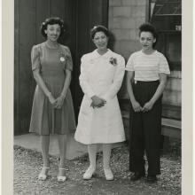 Three women stand outside a building