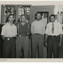 Four men stand inside an industrial building