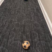 Two soccer balls sit in  vertical line in a hallway.