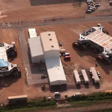 Two giant mobile launch crawlers seen from above next to a building.