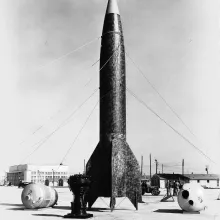 Large rocket sits in an open field.