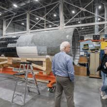 The individuals having a discussion in a restoration hangar.