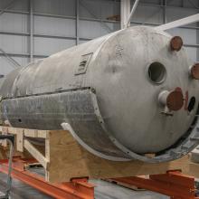 A large propellant tank sits on top of a wooden platform.