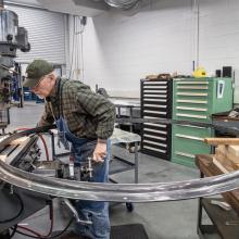 A man works on a large circular rocket part.