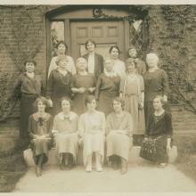 Several older women stand in front of a door in a sepia tone photograph.