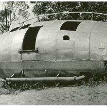 An oblong metal structure that has crashed into the tree line.