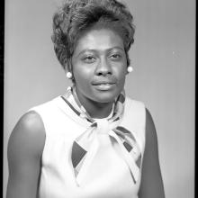 A black and white photograph of a Black woman in 1960s attire.