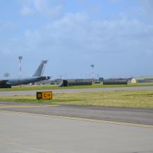 A large aircraft on a runway where a taxiway sign is visible.