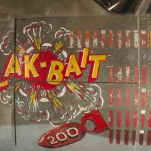 On the side of a bomber, the name "Flak-Bait" is painted, as well as an icon of a bomb with the number 200 on it and the name "O.J. Red Redmond."