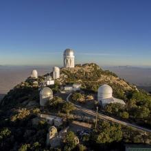 : Eight white buildings located on top of a mountain - six of them have domed tops while the other have regular pitched roofs. 