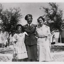 A woman in uniform poses for a picture with two other women to the left and right of her.