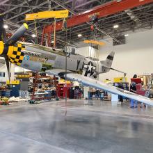 An aircraft hangs from the ceiling in an interior room under construction.