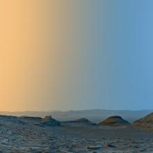 Panoramic view of the Martian surface at twilight with a clear sky transitioning from blue to orange gradient.