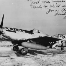 Vintage photo of the "Old Crow," a World War II military aircraft parked on a sandy area. Cursive writing across the top reads, "Just one more pass, Good luck & we'll set course - Your Pal Andy."