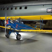 A blue biplane with yellow wings and a silver propeller. The number "2" is painted prominently on the side. 