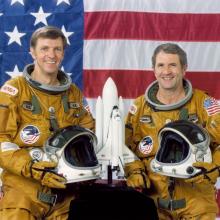 Two astronauts pose for their official NASA portraits.