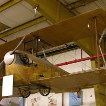 K-III airplane hangs from the ceiling inside a facility.