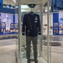 A space themed military uniform on display in a glass enclosure at a museum.