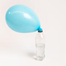 A blue balloon attatched to an empty water bottle is inflated by the gases that were created in the bottle.