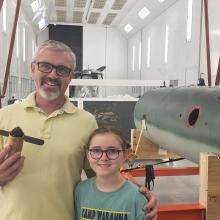 A person holds an airlog propeller in his hand as he poses for a picture.