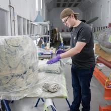 A person inspecting components of a missile in a restoration hangar.